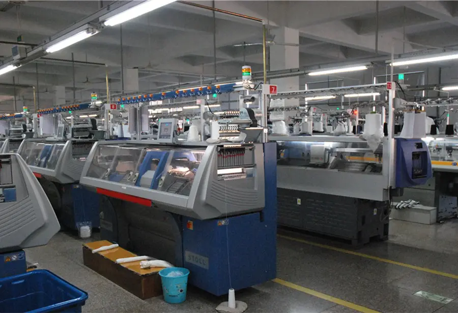Rows of computerized knitting machines in a production workshop.